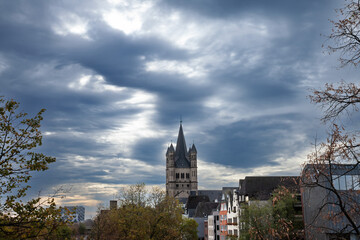 Naklejka premium Main tower of the Gross Sankt Martin Kirche seen from afar in a cologne landscape during a cloudy afternoon. The Great Saint Martin Church is a Roman catholic medieval church in Cologne, Germany.