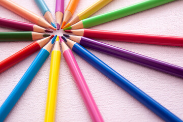 Fototapeta premium Colorful pencils in circle composition on pink background, art education card with stationery and copy space
