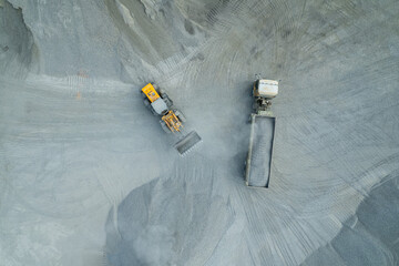 Sand loaders are shoveling rocks into dump trucks.