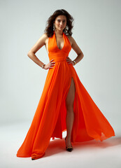 Sexy Fashion Model in Orange Dress with Wavy Hair Style showing leg