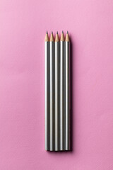 Group of silver pencils with pink vibrant background. Unity and togetherness concept.