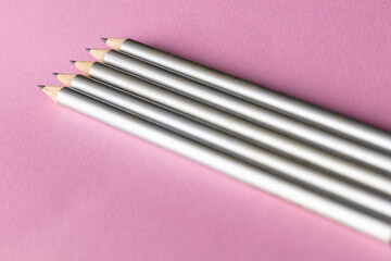 Group of silver pencils with pink vibrant background. Unity and togetherness concept.