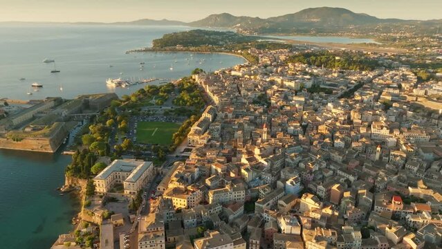 Flying over buildings, park and sea in Kerkyra, Corfu island. Aerial morning shot of Kerkyra, capital of Corfu island, Greece