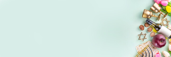 Passover, Pesah background. jewish Easter Passover spring holiday celebration, with accessories - menorah, matzo, spring flowers, wine bottle, gold wine glass, jewish david stars, copy space top view 