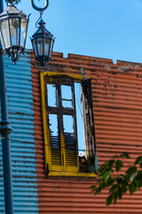 Old wooden window with yellow shutters and street lamp on blue wall