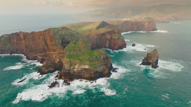 Flying over bizarre brown-green rocks of Ponta de Sao Lourenco, Madeira island, Portugal. Atlantic ocean waves crashing over the rocks of Madeira island. Aerial drone shot, 4K