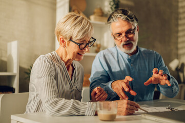 Senior couple sitting at table and looking into blueprints of their new home