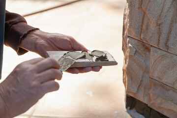 Hand applies mortar to stone tiles close-up..
