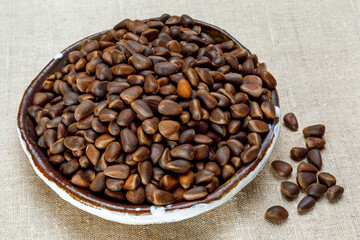 Pine nuts in their shells on a plate. The seeds of the Siberian pine Pinus Sibirica. Pine nuts are rich in vitamins, minerals and amino acids and are used in traditional medicine