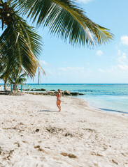 Girl walking on white sand beach in Mahahual, Mexico