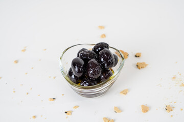 Top view of black olives marinated with olive oil in glass bowl isolated on white background.