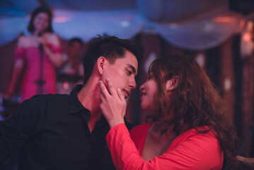 A sexy woman affectionately touches the man's faces as she draws her lips close to his to attempt a kiss. A private and romantic moment between a couple.