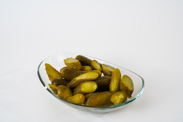 Top view of sliced pickled gherkins on glass plate isolated on white background.