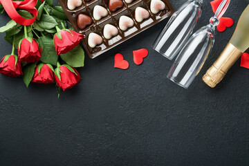 Valentines day card. Rose red flowers brownie cookies and chocolate candy on heart shaped, gift box with wine on black background. Mothers or Womens Day greeting card. Top view flat lay