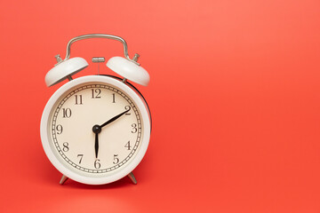 Retro alarm clock on red table background, vintage style
