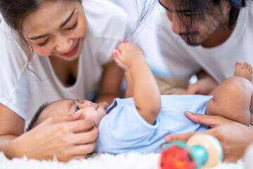 Mom and father happy joyful playing asian infant baby new born have fun looking to parent face