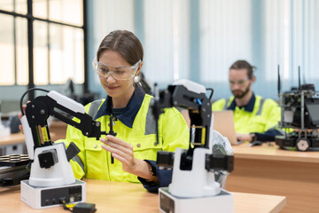 Female engineer training programmable and design AI robot arm simulation in academy robotics automation laboratory room for use in manufacturing or industry