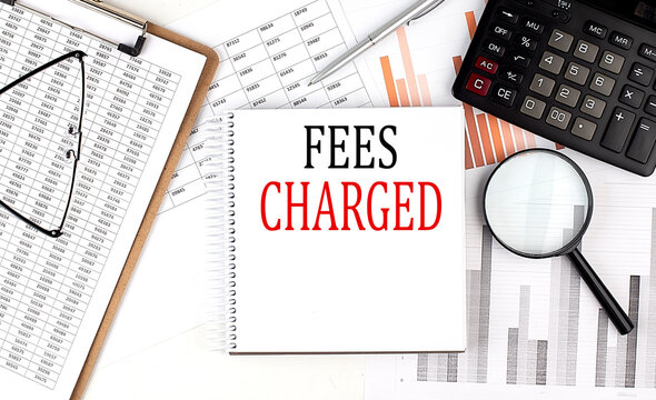 FEES CHARGED text on notebook with clipboard and calculator on a chart background - Powered by Adobe