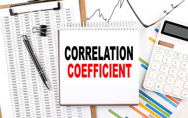 CORRELATION COEFFICIENT text on notebook with chart, calculator and pen