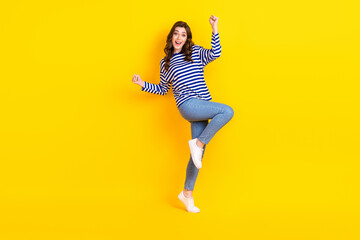 Fototapeta na wymiar Full length photo of lovely young lady excited raise fists win lottery wear trendy striped garment isolated on yellow color background