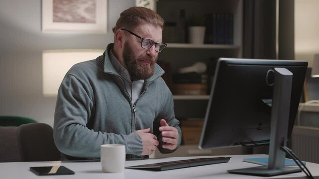 Mature bearded man suffering from heartache while working on computer, heart desease concept