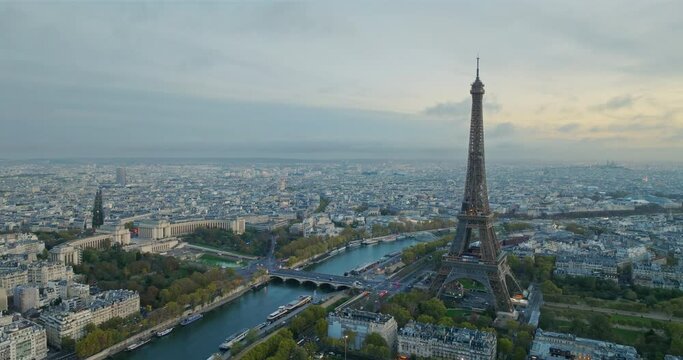 Beautiful view of famous Eiffel Tower in France with magical morning cloud and fog. Wide establishing aerial drone fly over seine river in paris city center, best travel destination landmark in Europe