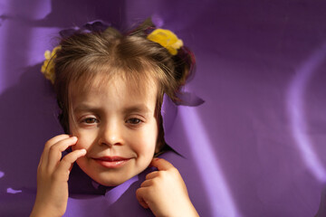 Cute girl smiling from hole in a paper