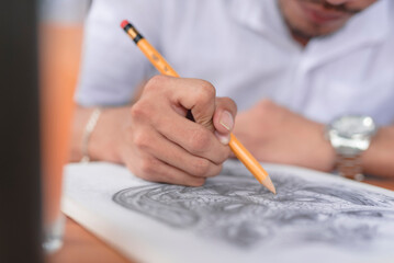 A skilled penciler firmly grips the pencil as he puts a shading effect on his amazing sketch.