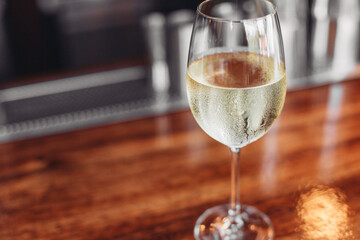 A glass of cold white wine, olives on a wooden table