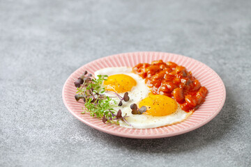 Continental breakfast - eggs, micro greens and beans in tomato sauce on a plate on the table. Healthy breakfast