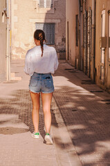 back, view, medium distance of, a female in shorts and white shirt, walking to school in Provence, France