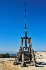 Back view, far distance of, a mid-evil, rock throwing weapon, against a blue sky