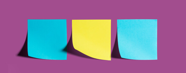 Paper office stickers blue and yellow colors with curved tips and shadow on  purple background
