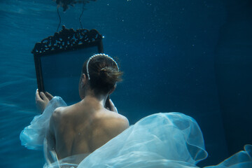 Back of young beautifull caucasian woman in wedding dress under water