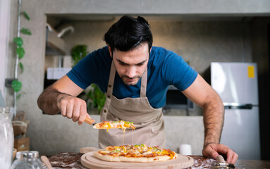handsome chef cut delicious homemade italian mozzarella pizza after prepare and bake from stove or oven for lunch meal or dinner in local italian pizza restaurant