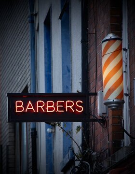 neon barbers sign and pole on the side of a building