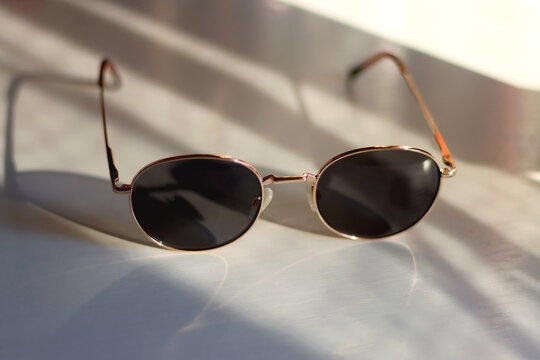 Retro round sunglasses on the table, illuminated by warm sunlight. Selective focus.