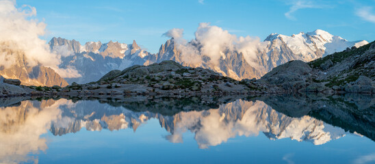 The panorama of Mont Blanc massif  Les Aiguilles towers and Grand Jorasses over the Lac Blanc lake in the sunset light.