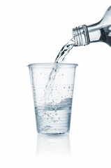Pouring water into disposable plastic cup on a white background