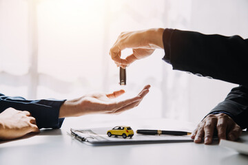 Hand holding car keys and car rental concept A close-up view of the agent, giving the customer the car keys after signing the lease, rental form and car name.