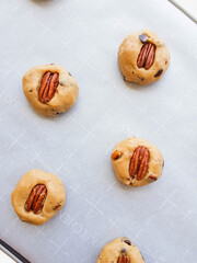 Homemade brown butter cookies with pecan nuts and milk chocolate on a tray and a parchment paper. Photo in process.