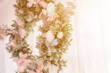 happy easter and spring holidays time. easter wreath with sprigs of lilac bush blossom flowers and leaves and decorated colorful eggs on bright light window background. home interior decor. flare