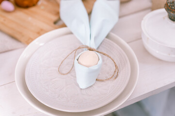 happy easter holiday in springtime season. festive home decor. traditional food. white beige chicken egg wrapped in a pale blue cloth like rabbit or bunny ears in a plate on the table