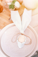 happy easter holiday in springtime season. festive home decor. traditional food. white beige chicken egg wrapped in a pale blue cloth like rabbit or bunny ears in a plate on the table. flare