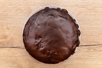 Chocolate cake topped with chocolate, lying on a plate with water droplets.