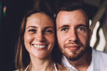 Close up portrait of cheerful male and female smiling at camera during love photo session for together time spending, funny Caucasial husband and wife posing during date with good vibes for recreation