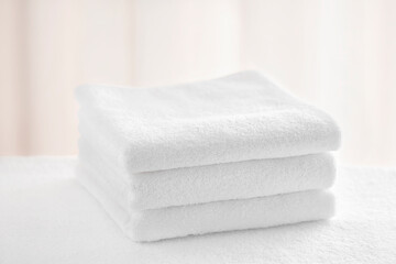 Three white terry towels on a light background in the bathroom