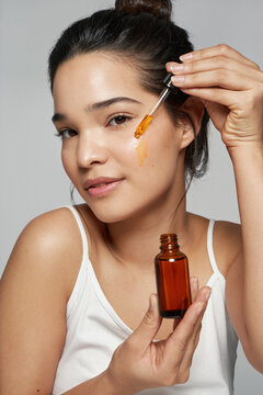 Woman applying oil on face