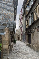 Fototapeta na wymiar Medieval half-timbered houses line cobblestone street in ancient city of Dinan