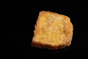 (Torrijas) Fried bread soaked in milk flavored with vanilla, cinnamon, lemon and egg on a black background. Typical Easter sweet. Concept of traditional and festive cuisine.